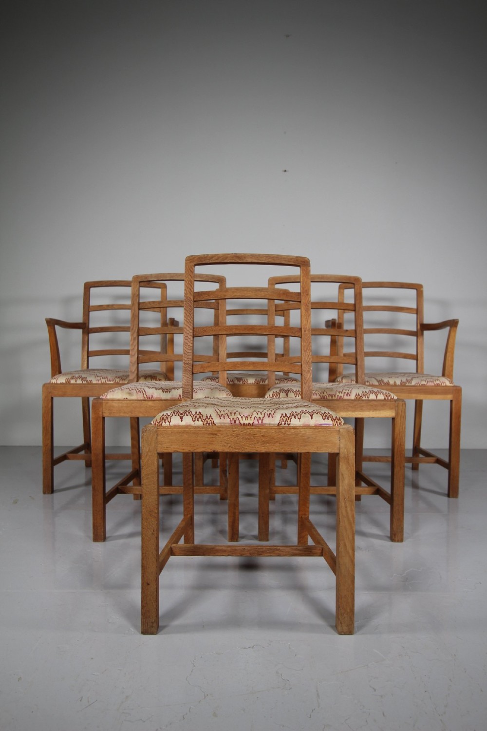 A set of six 1920s oak dining chairs including two armchairs, featuring structured horizontal ladder backs and patterned fabric upholstered seats. View III