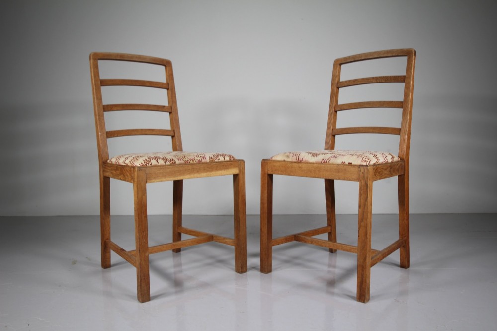 A set of six 1920s oak dining chairs including two armchairs, featuring structured horizontal ladder backs and patterned fabric upholstered seats. View VI