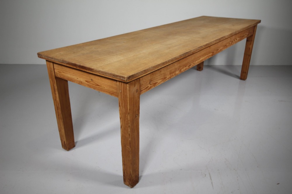 A large 19th-century English pine dining table featuring a solid plank top and four simple square legs.