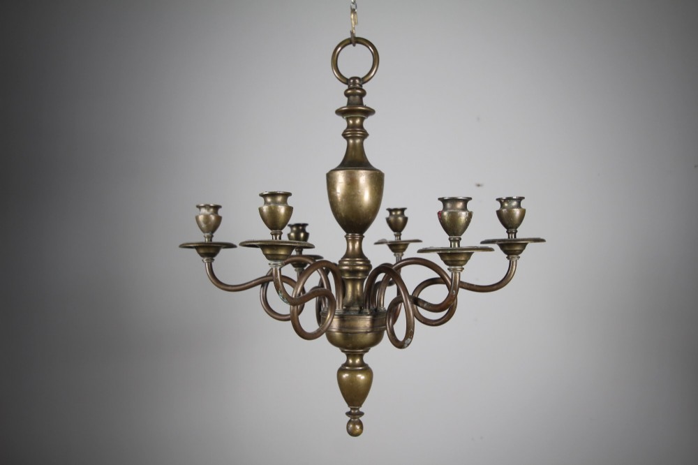 A 19th-century cast bronze six-arm chandelier featuring a central turned baluster stem, scrolled branches, and candle sconces.