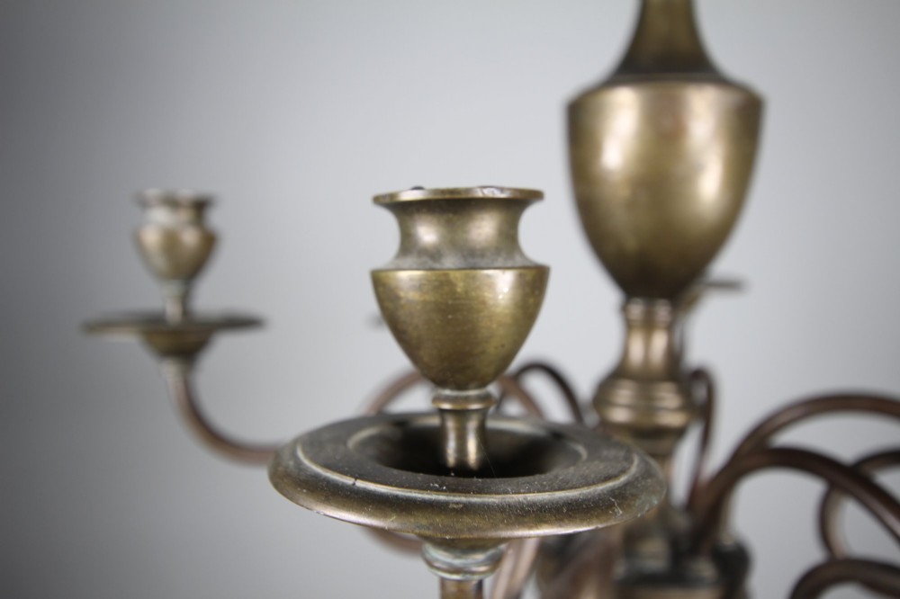 A 19th-century cast bronze six-arm chandelier featuring a central turned baluster stem, scrolled branches, and candle sconces. View V