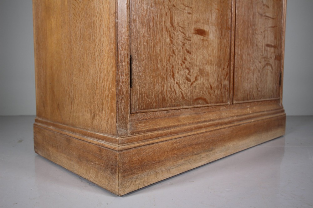 A tall light oak two-door wardrobe featuring octagonal upper panels, quarter-sawn wood grain, and small turned knobs on a plinth base. View V