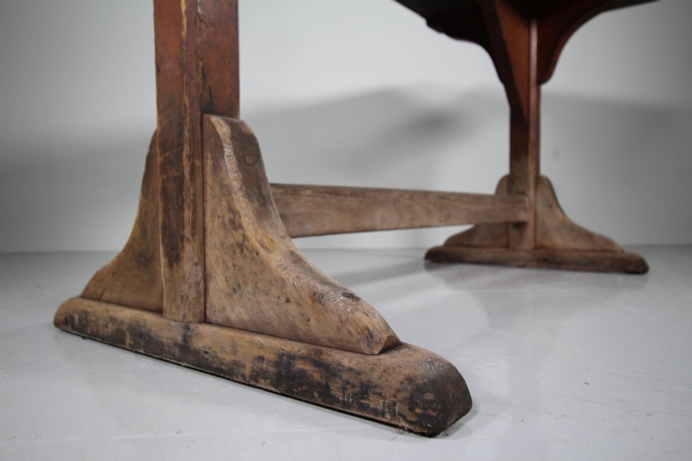 An antique 19th-century English tavern table featuring a scrubbed pine top resting on a red painted trestle base with a central stretcher. View VII