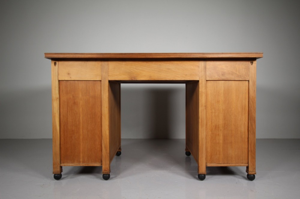 A light oak kneehole writing desk with nine drawers featuring square ebonised handles and ebonised ball feet. View II