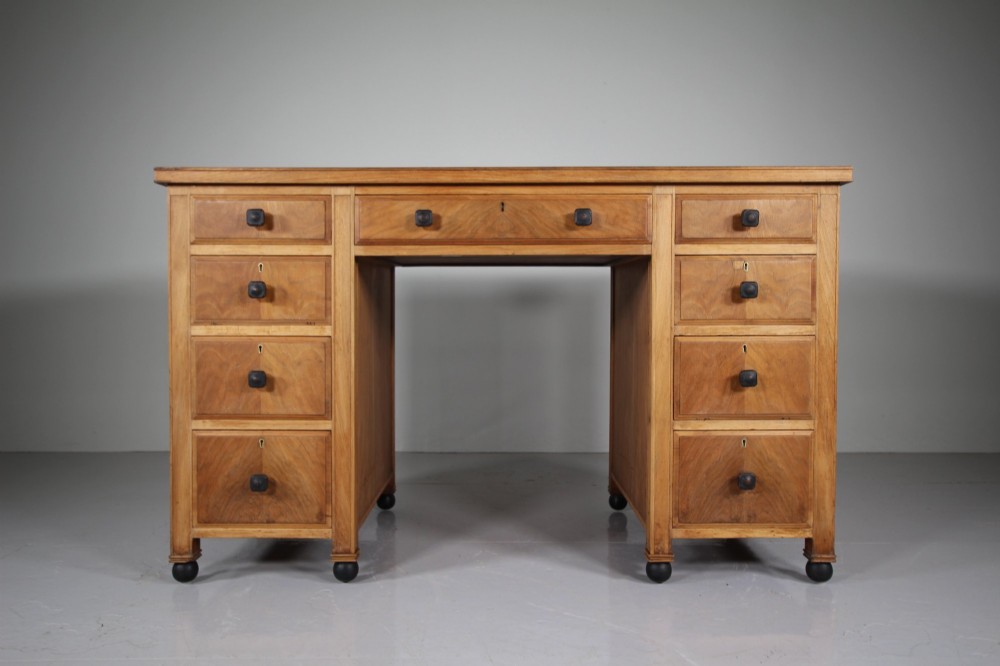 A light oak kneehole writing desk with nine drawers featuring square ebonised handles and ebonised ball feet. View III