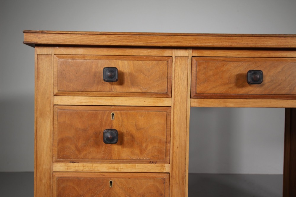 A light oak kneehole writing desk with nine drawers featuring square ebonised handles and ebonised ball feet. View IV