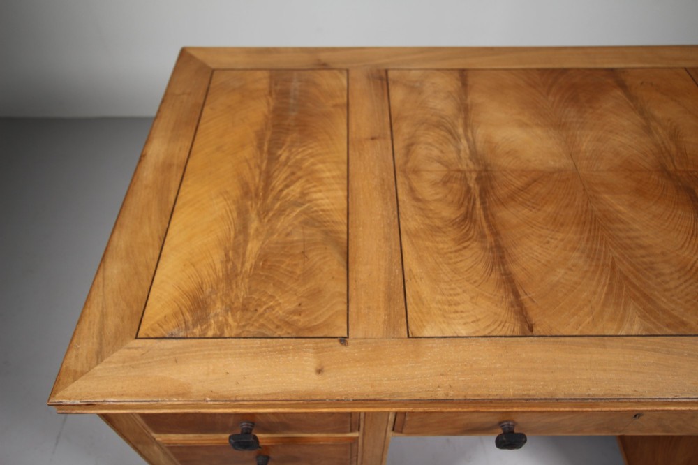 A light oak kneehole writing desk with nine drawers featuring square ebonised handles and ebonised ball feet. View VI