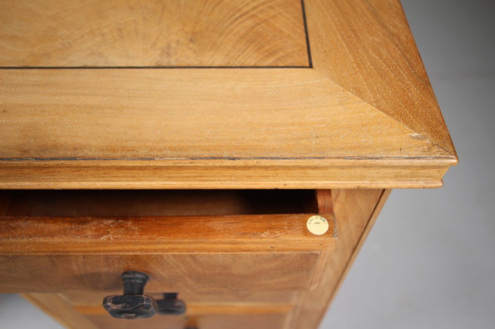 A light oak kneehole writing desk with nine drawers featuring square ebonised handles and ebonised ball feet. View VII