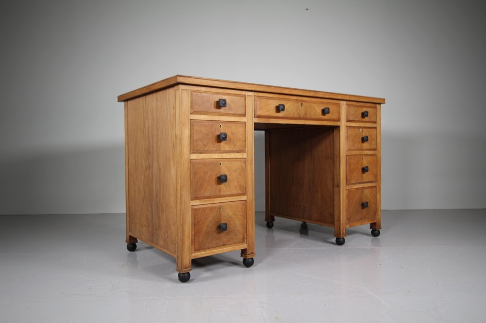 A light oak kneehole writing desk with nine drawers featuring square ebonised handles and ebonised ball feet. View VIII