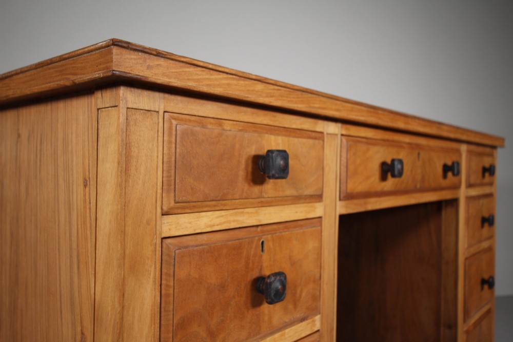 A light oak kneehole writing desk with nine drawers featuring square ebonised handles and ebonised ball feet. View IX