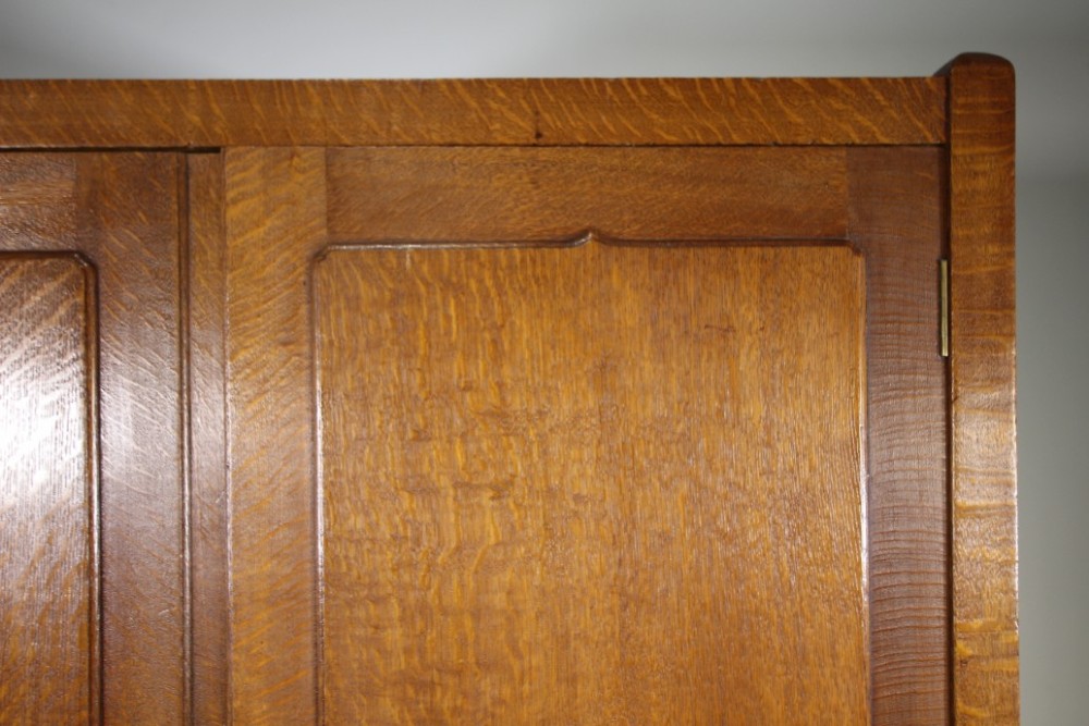 An Arts and Crafts solid oak double-door wardrobe featuring flat recessed timber panels, small round wooden door handles, and straight square feet. View IV