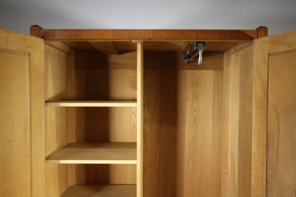 An Arts and Crafts solid oak double-door wardrobe featuring flat recessed timber panels, small round wooden door handles, and straight square feet. View VI