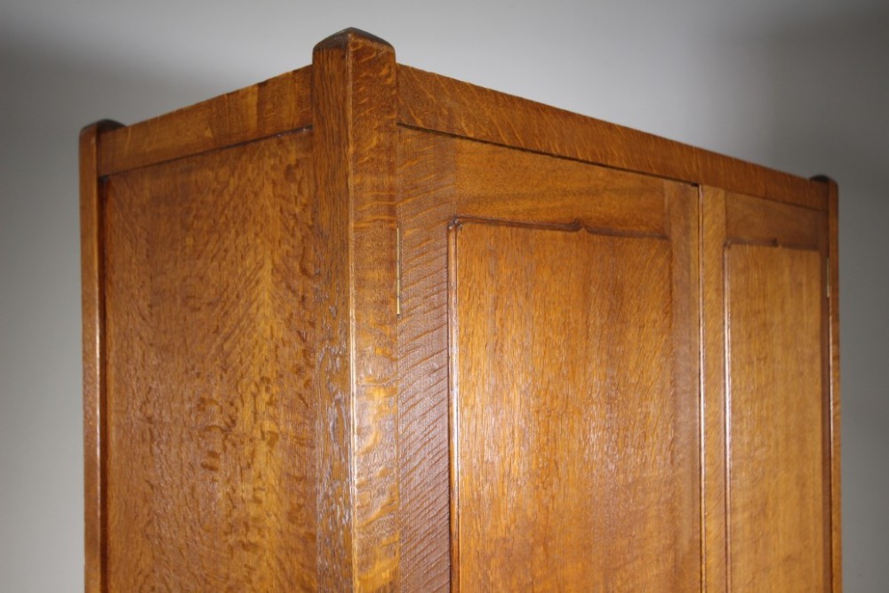 An Arts and Crafts solid oak double-door wardrobe featuring flat recessed timber panels, small round wooden door handles, and straight square feet. View VII