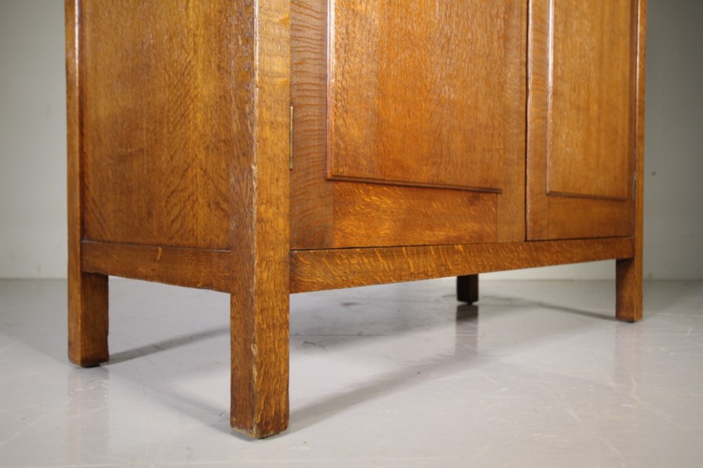 An Arts and Crafts solid oak double-door wardrobe featuring flat recessed timber panels, small round wooden door handles, and straight square feet. View VIII