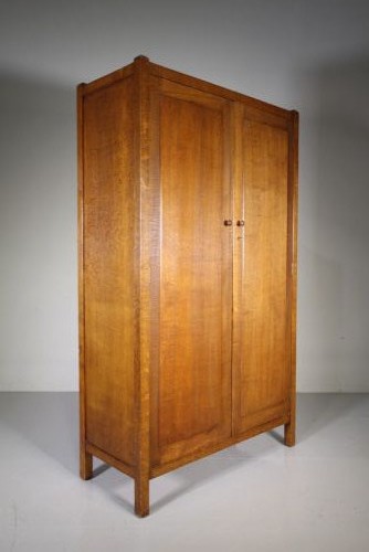 An Arts and Crafts solid oak double-door wardrobe featuring flat recessed timber panels, small round wooden door handles, and straight square feet. View II