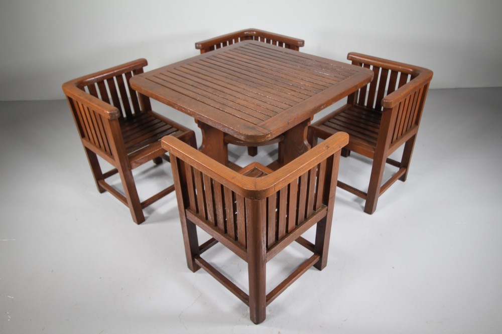 A 1920s slatted teak garden dining set featuring a square table and four corner chairs that tuck flush under the tabletop. View II