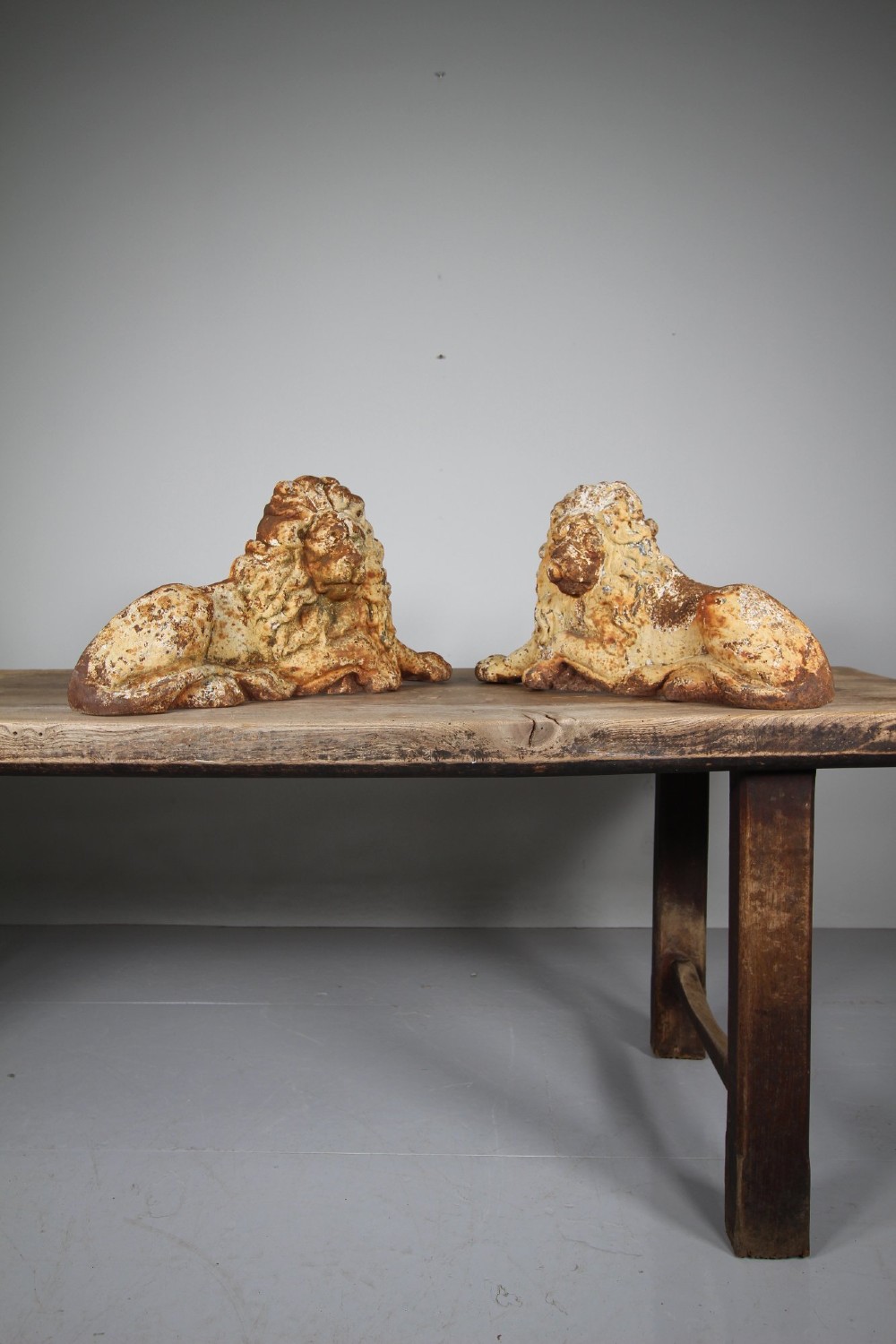 A pair of 19th-century cast iron recumbent lion boot scrapers featuring weathered cream paint and visible rust patination. View II