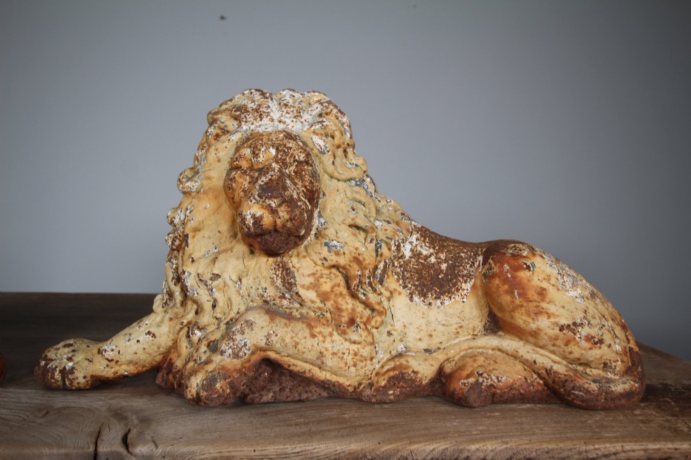 A pair of 19th-century cast iron recumbent lion boot scrapers featuring weathered cream paint and visible rust patination. View VI