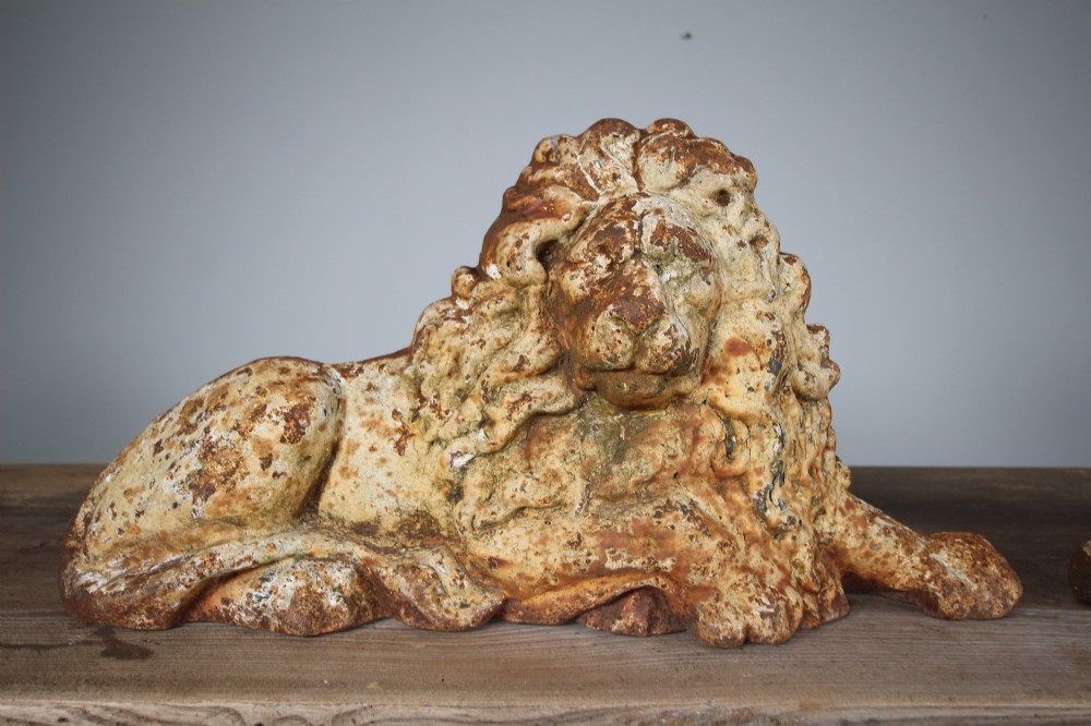 A pair of 19th-century cast iron recumbent lion boot scrapers featuring weathered cream paint and visible rust patination. View VII