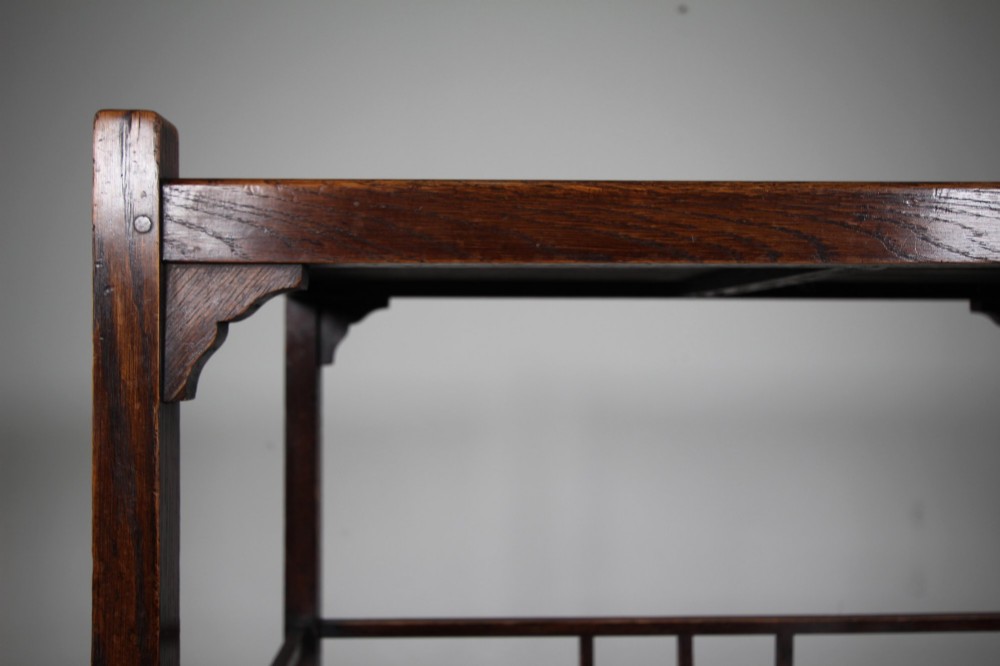 A dark oak three-tiered Edwardian trolley featuring slatted shelf galleries and castor wheels. View IV