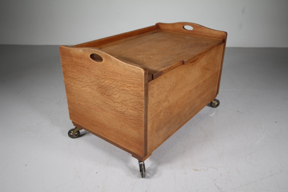 A rectangular warm brown oak bedding box featuring side cut-out handles, a top lid, and four small metal castors. View II