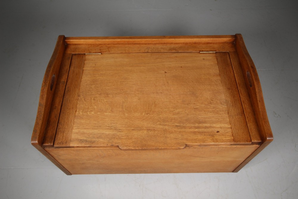 A rectangular warm brown oak bedding box featuring side cut-out handles, a top lid, and four small metal castors. View III