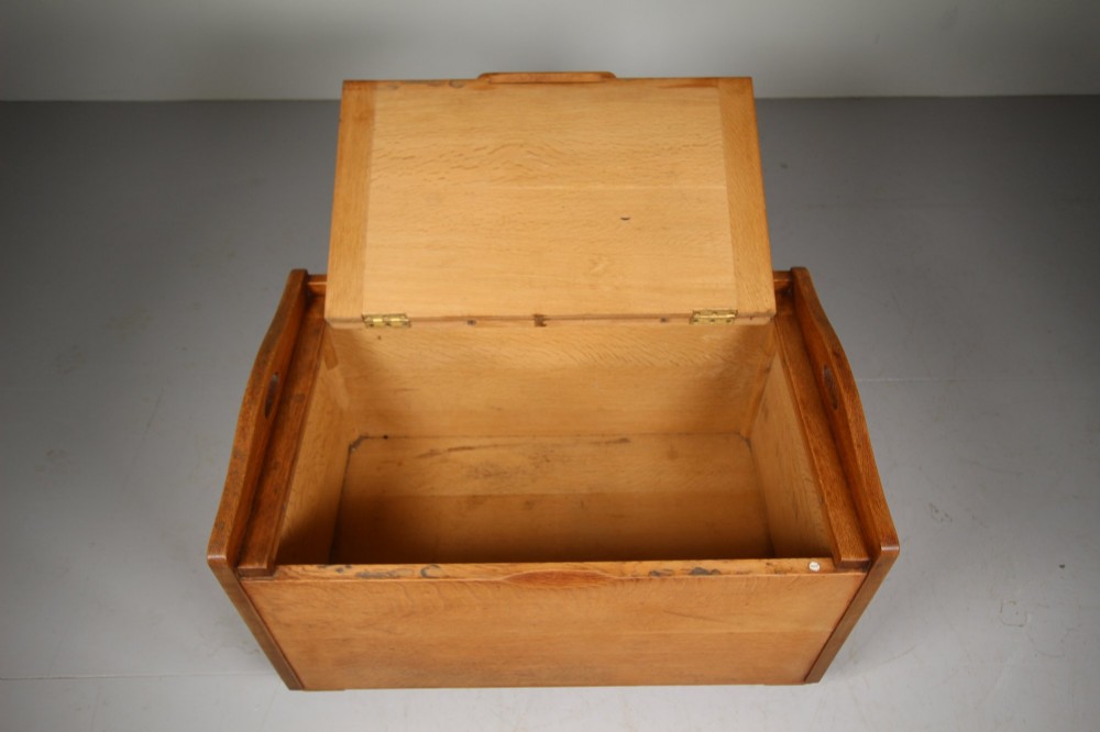 A rectangular warm brown oak bedding box featuring side cut-out handles, a top lid, and four small metal castors. View IV