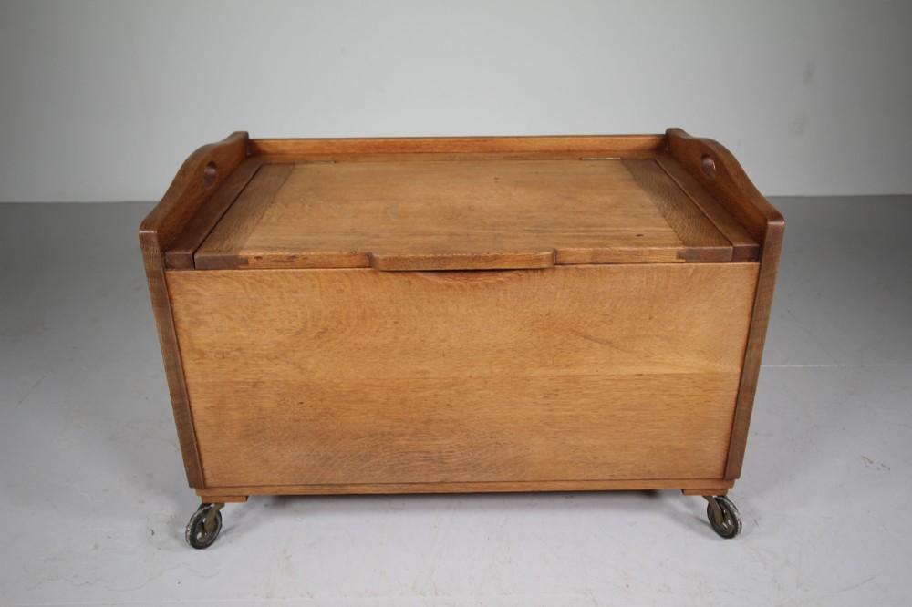 A rectangular warm brown oak bedding box featuring side cut-out handles, a top lid, and four small metal castors. View VI