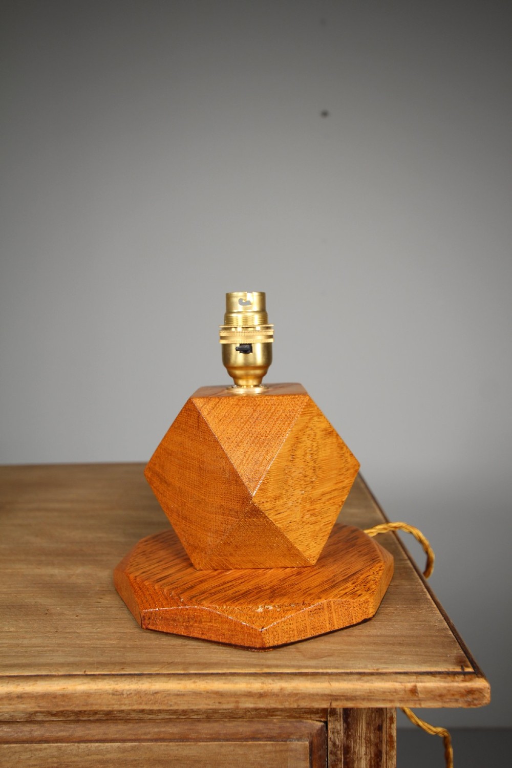 A 1920s geometric oak table lamp base featuring a faceted polyhedral stem set on an octagonal stepped wooden base with a brass socket.