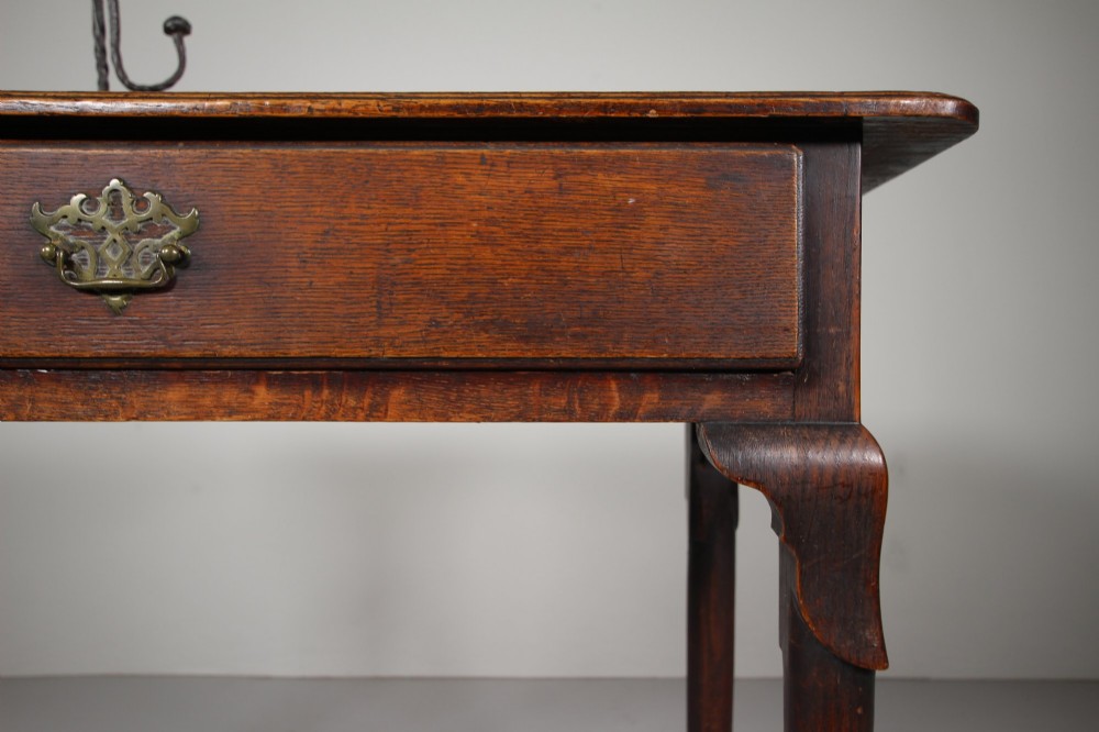 A Georgian dark oak side table featuring a single drawer with a brass handle, raised on slender tapered legs terminating in pad feet. View IV