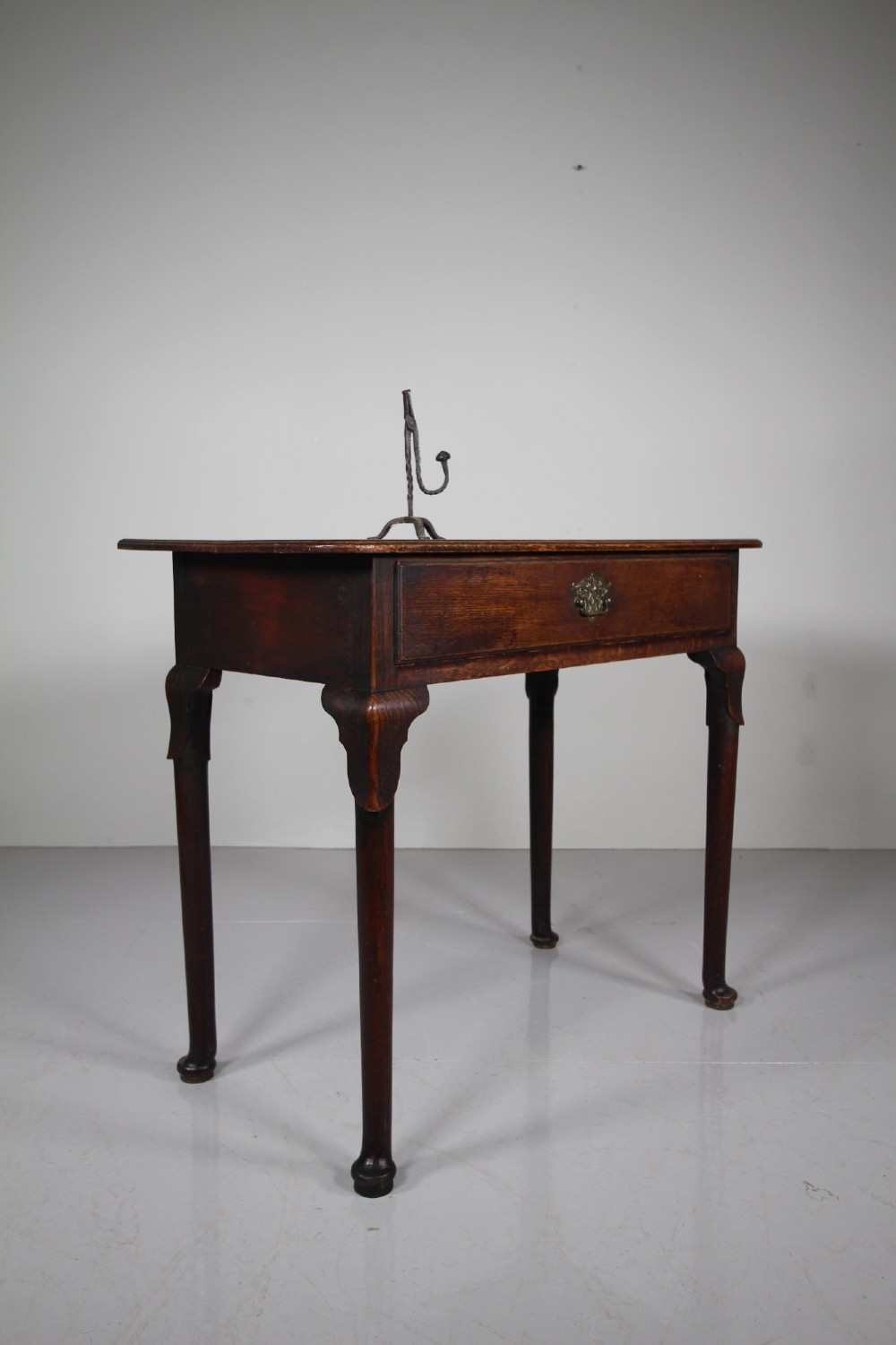A Georgian dark oak side table featuring a single drawer with a brass handle, raised on slender tapered legs terminating in pad feet. View V