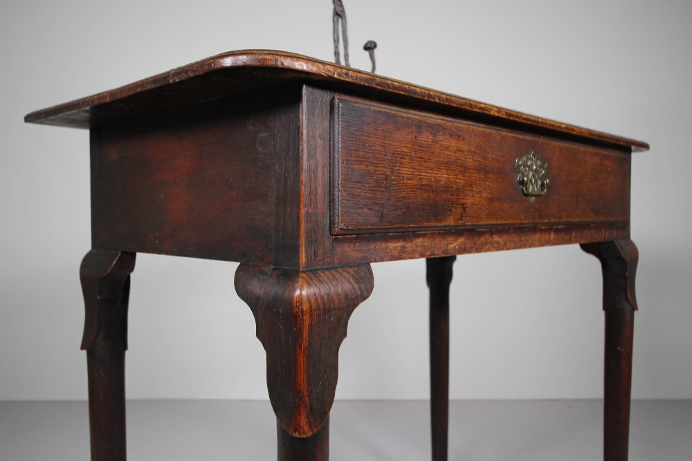 A Georgian dark oak side table featuring a single drawer with a brass handle, raised on slender tapered legs terminating in pad feet. View VI
