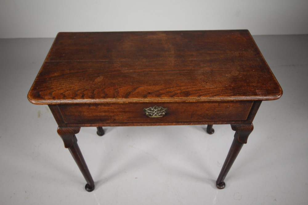 A Georgian dark oak side table featuring a single drawer with a brass handle, raised on slender tapered legs terminating in pad feet. View VII