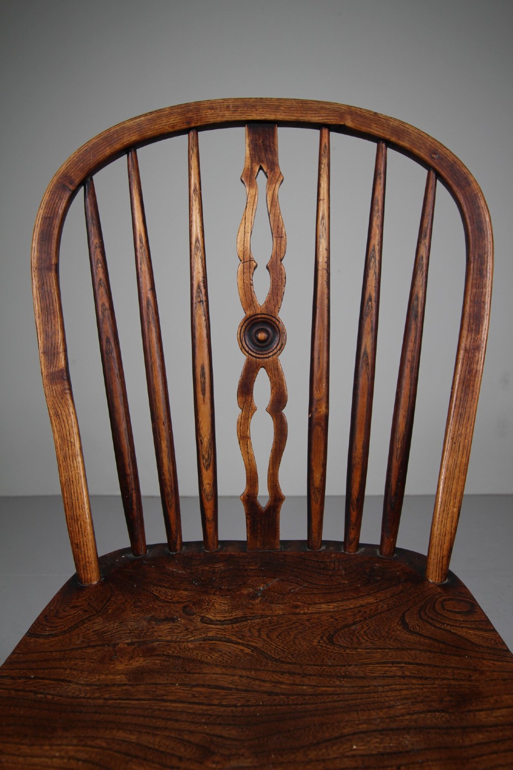 An early 19th-century hoop back Windsor chair crafted from dark elm, featuring a pierced central splat, turned legs, and a contoured saddle seat. View IV