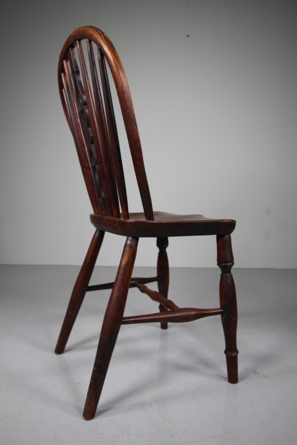 An early 19th-century hoop back Windsor chair crafted from dark elm, featuring a pierced central splat, turned legs, and a contoured saddle seat. View VI
