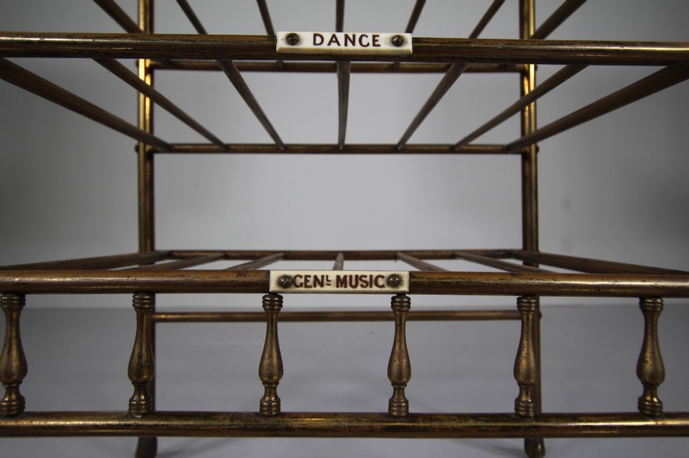 A 19th-century English Victorian brass and mahogany sheet music stand featuring open slatted shelves with ceramic labels, a top drawer, and a mirrored upper gallery. View IV