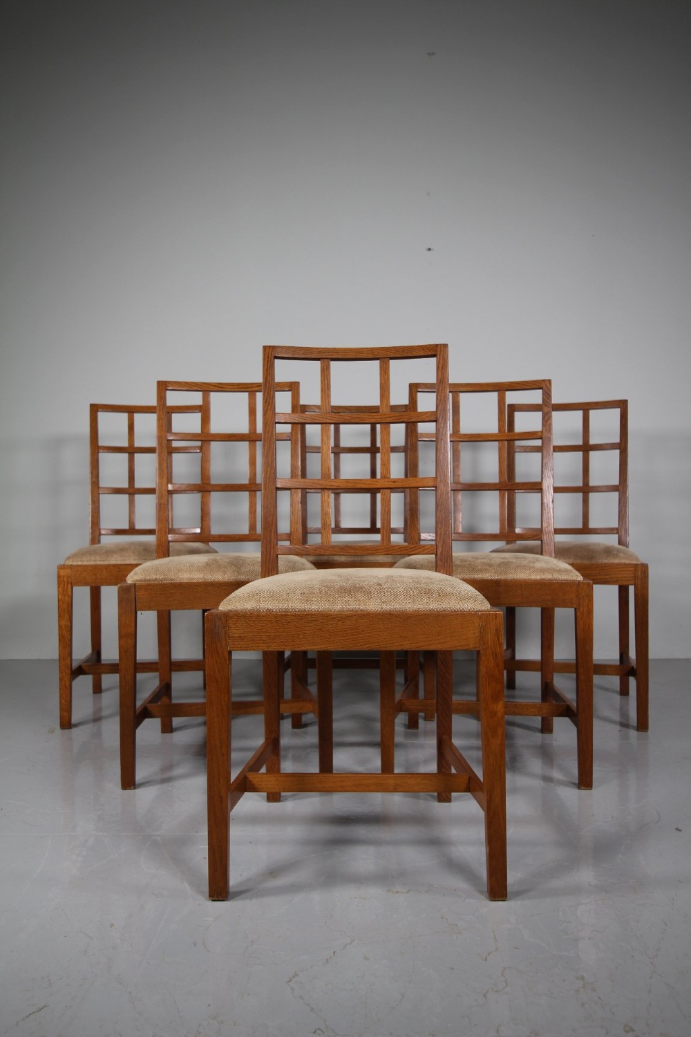 A set of six 1930s solid oak dining chairs featuring geometric lattice backs and upholstered neutral fabric seats. View VI
