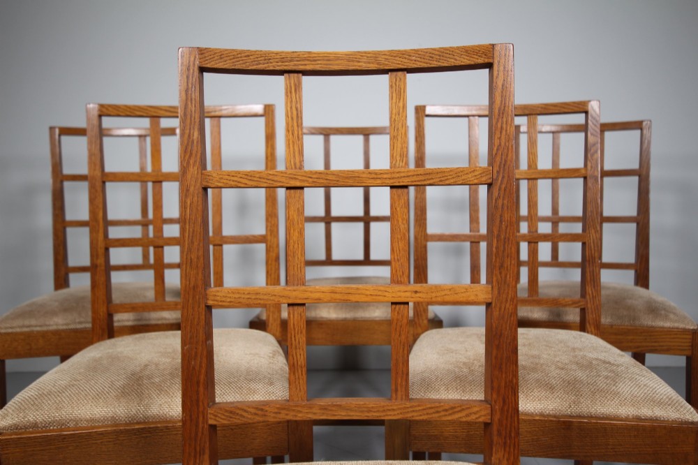 A set of six 1930s solid oak dining chairs featuring geometric lattice backs and upholstered neutral fabric seats. View IX