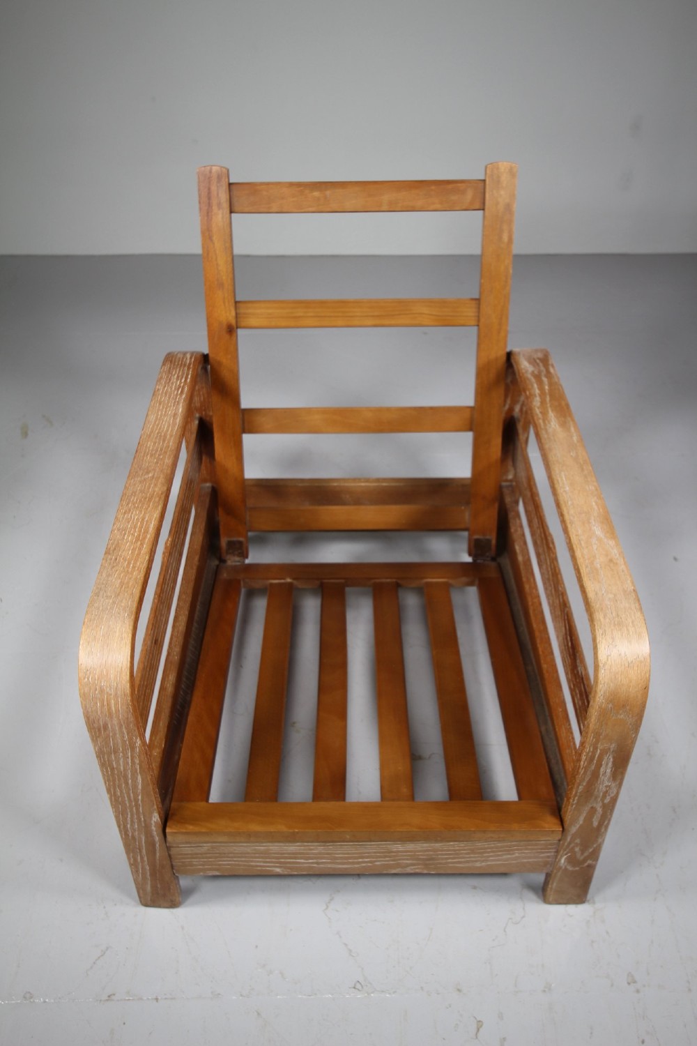 A 1930s solid oak reclining armchair frame featuring curved bentwood armrests, a slatted timber backrest, and an un-upholstered seat base. View II