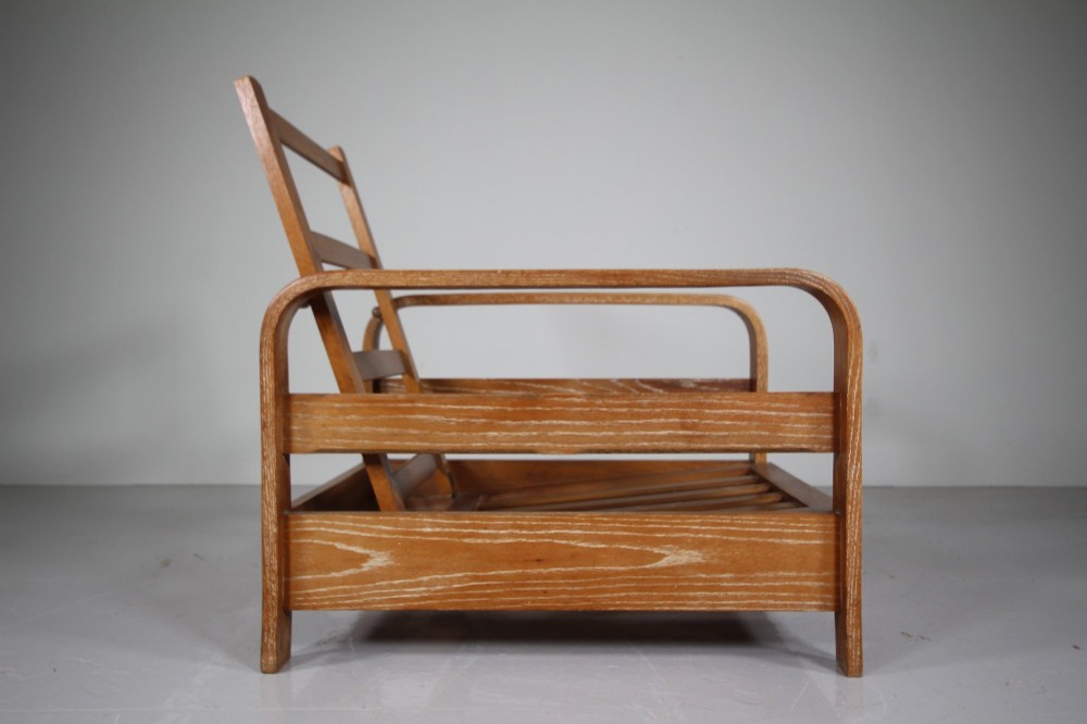 A 1930s solid oak reclining armchair frame featuring curved bentwood armrests, a slatted timber backrest, and an un-upholstered seat base. View IV