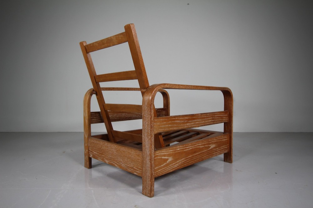 A 1930s solid oak reclining armchair frame featuring curved bentwood armrests, a slatted timber backrest, and an un-upholstered seat base. View V