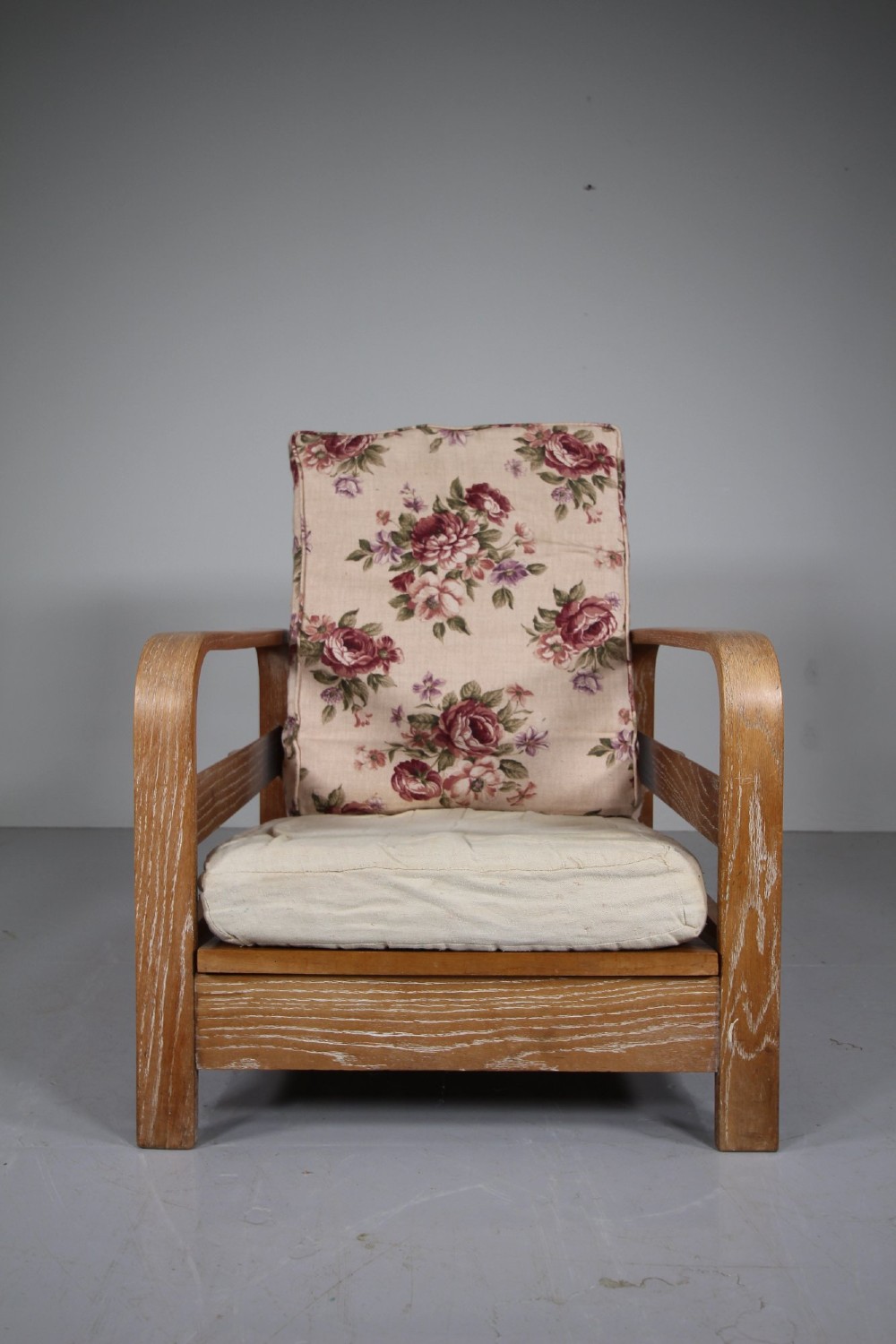 A 1930s solid oak reclining armchair frame featuring curved bentwood armrests, a slatted timber backrest, and an un-upholstered seat base. View VII
