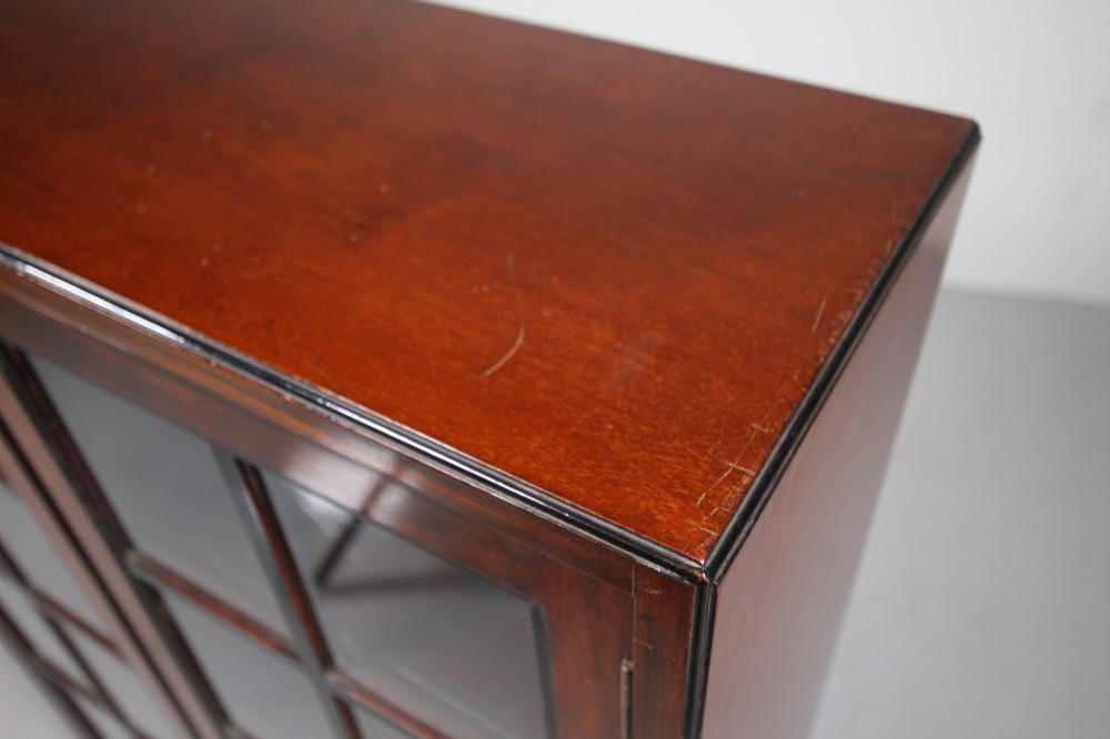 A 1920s Heals mahogany bookcase featuring two glazed doors with multi-pane glass and dark turned bun feet. View II
