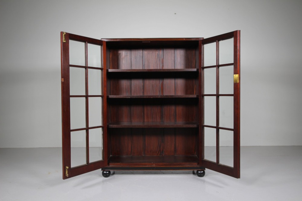 A 1920s Heals mahogany bookcase featuring two glazed doors with multi-pane glass and dark turned bun feet. View IV