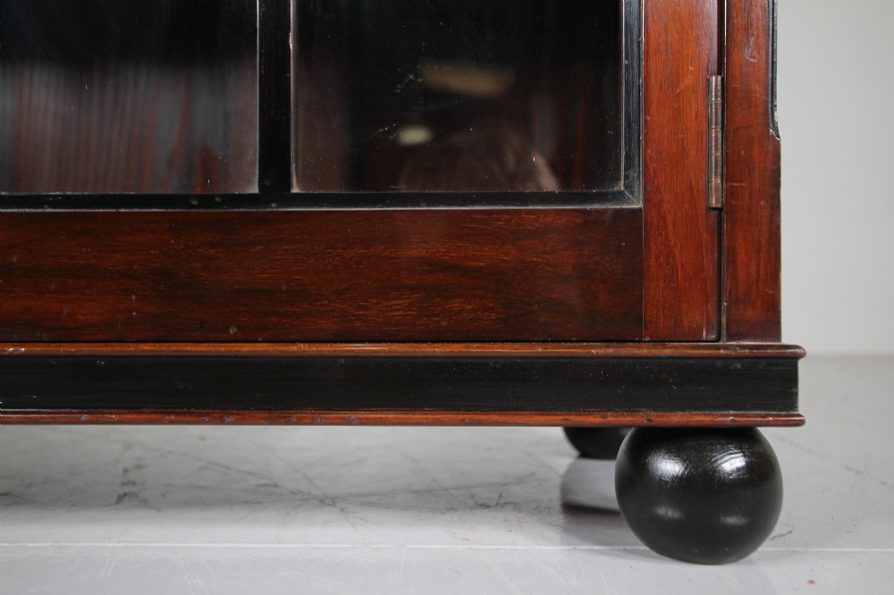 A 1920s Heals mahogany bookcase featuring two glazed doors with multi-pane glass and dark turned bun feet. View VI
