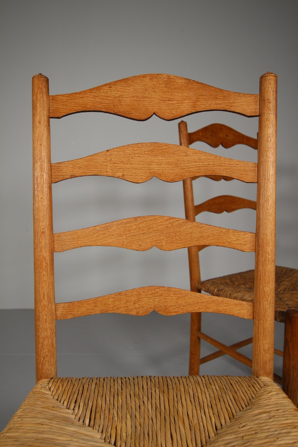 A pair of Arts and Crafts oak ladderback side chairs featuring hand-woven rush seats and four shaped back slats. View IV