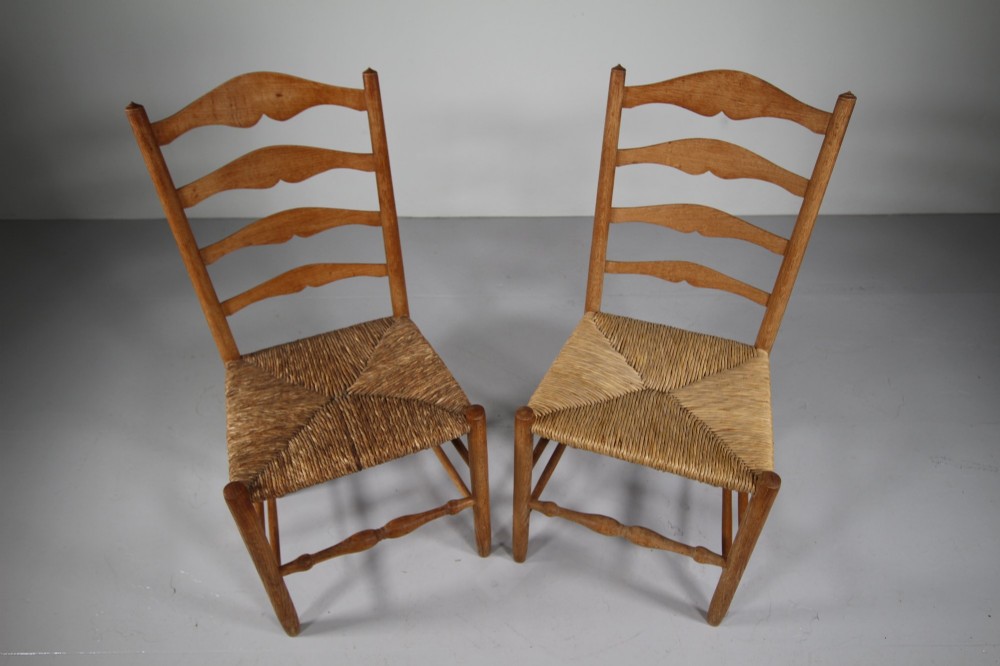 A pair of Arts and Crafts oak ladderback side chairs featuring hand-woven rush seats and four shaped back slats. View V