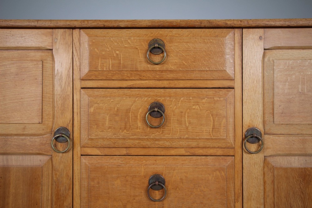 A light oak dresser base from the 1930s featuring a central stack of four drawers flanked by two panelled cupboard doors with brass ring handles. View III