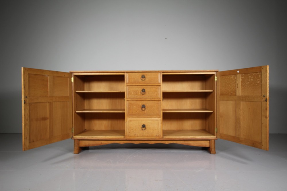 A light oak dresser base from the 1930s featuring a central stack of four drawers flanked by two panelled cupboard doors with brass ring handles. View IV