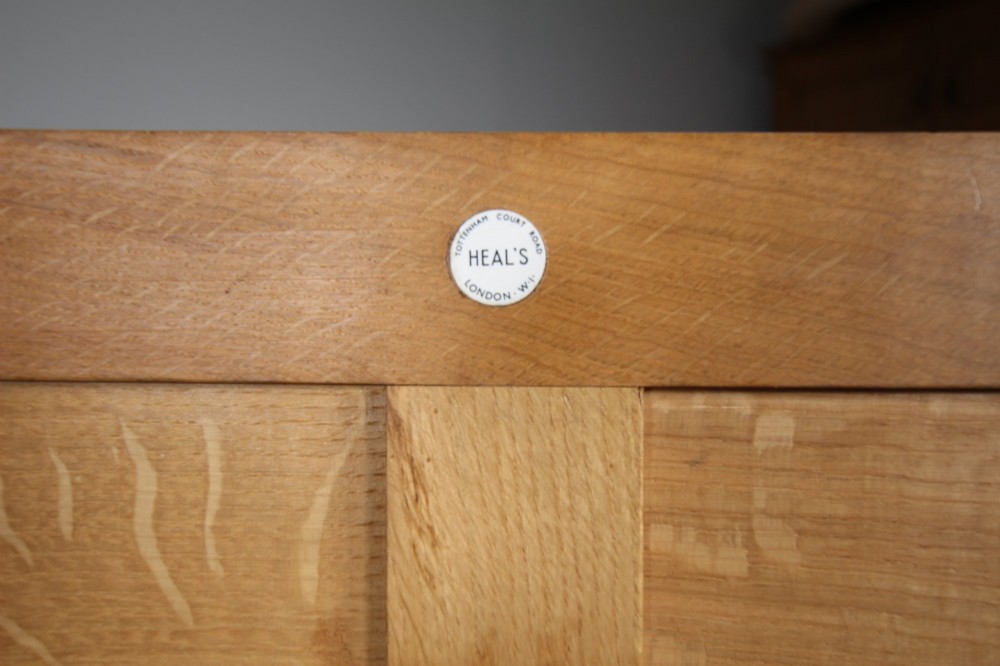 A light oak dresser base from the 1930s featuring a central stack of four drawers flanked by two panelled cupboard doors with brass ring handles. View V